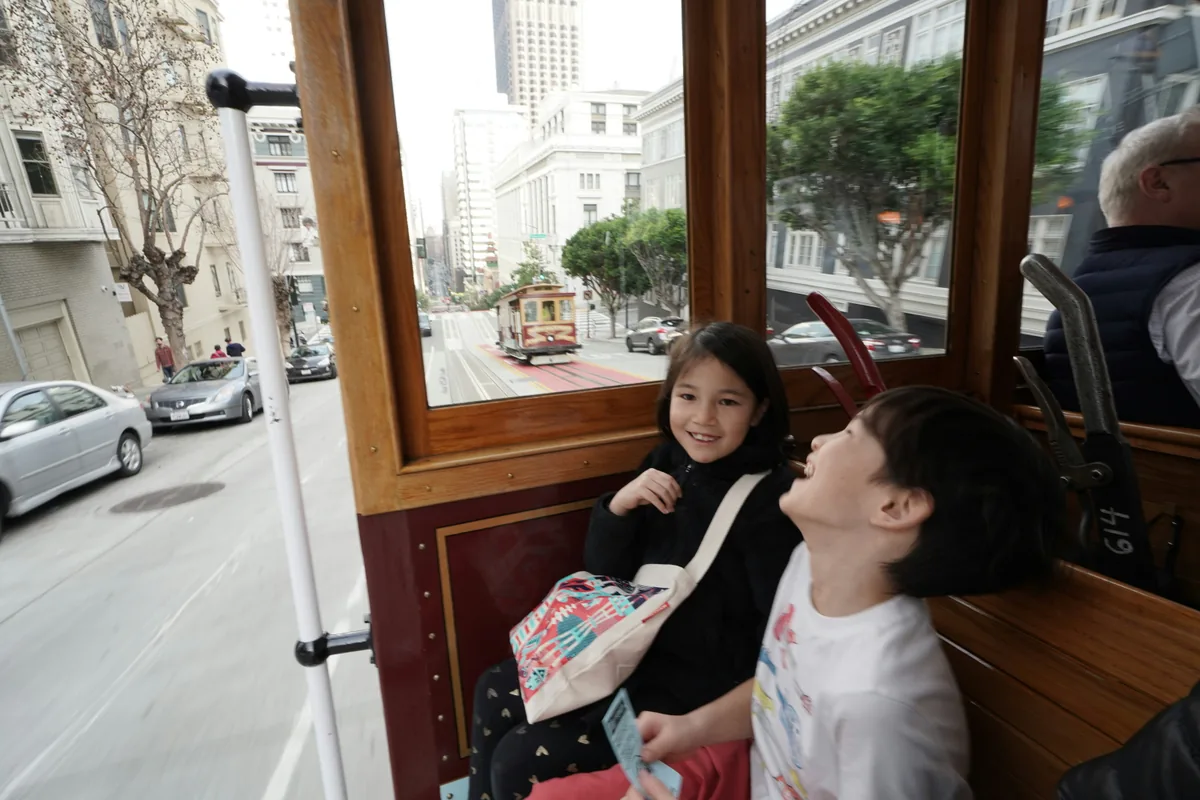 Two children riding a San Francisco cable car.