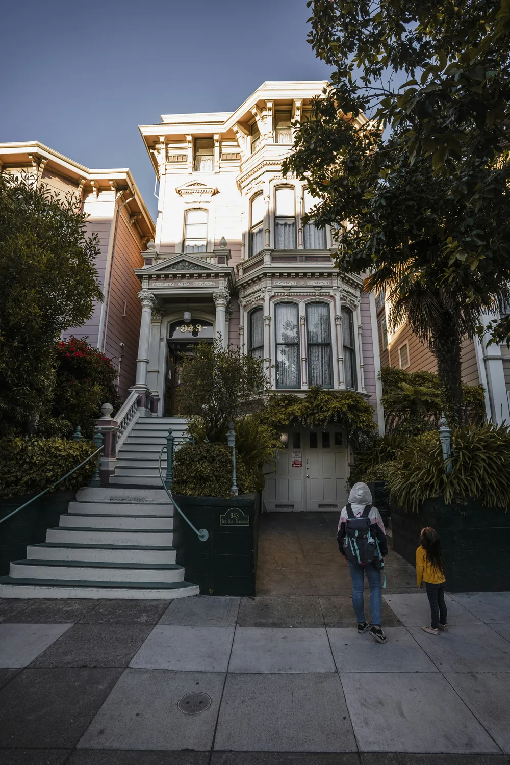 An adult and child walking toward a San Francisco Victorian home.