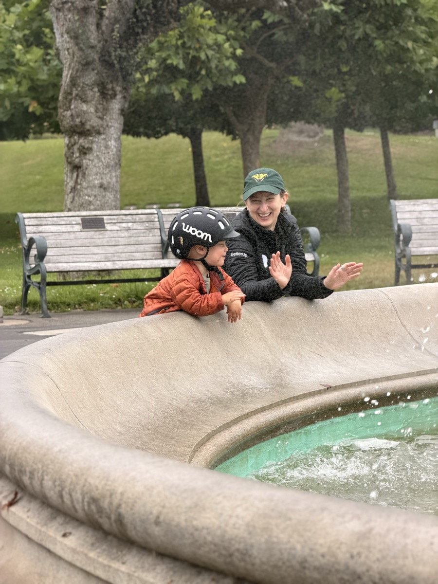 A mother and child sharing a happy moment beside a fountain.